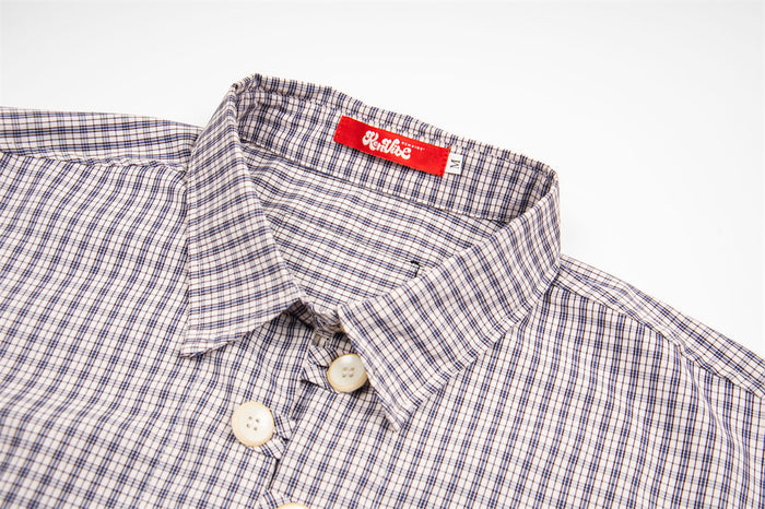 Close-up of the light beige plaid shirt collar, top buttons, and red neck label