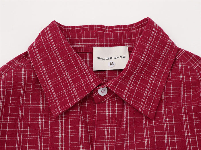 Close-up of the red plaid shirt collar, button, woven check pattern, and Savage Base label