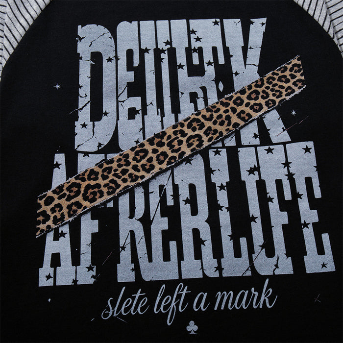 Close-up of the tee’s distressed gray lettering, diagonal leopard-print stripe, stars, and cursive text