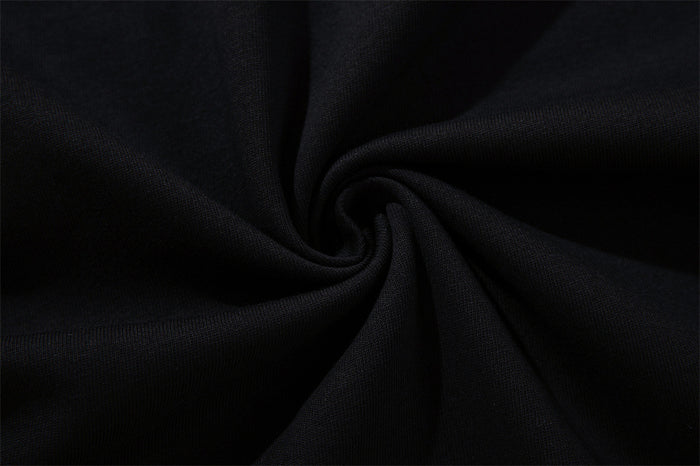 Close-up of the tee’s black fabric gathered into a twist, showing its fine woven texture