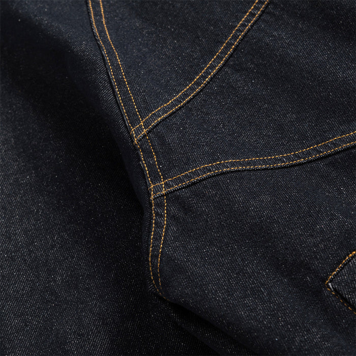 Close-up of curved dark denim panel seams with contrasting gold double stitching