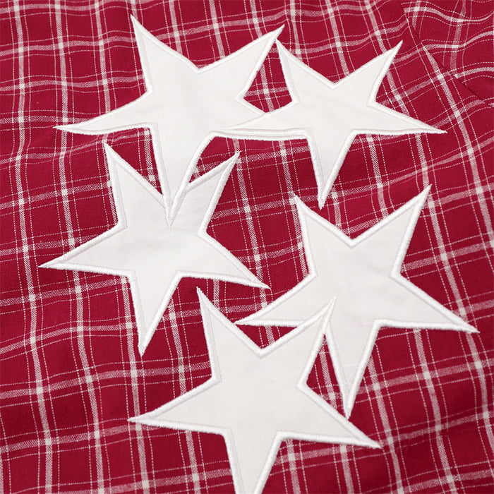 Close-up of four white star-shaped patches attached to the red plaid shirt chest