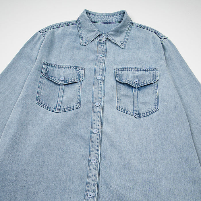 Close front view of the light wash denim shirt showing the pointed collar, buttons, and two flap chest pockets