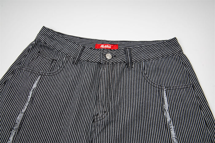 Close-up of the striped jeans waistband, button fastening, belt loops, and front pocket openings