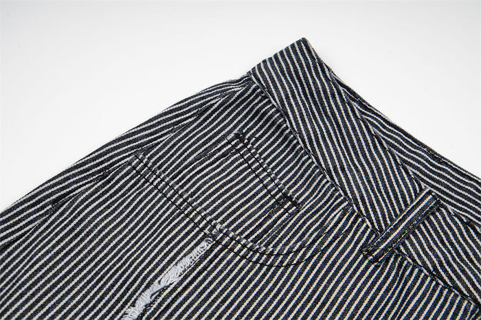 Close-up of a front pocket corner and waistband on black and white striped jeans with exposed seam detailing