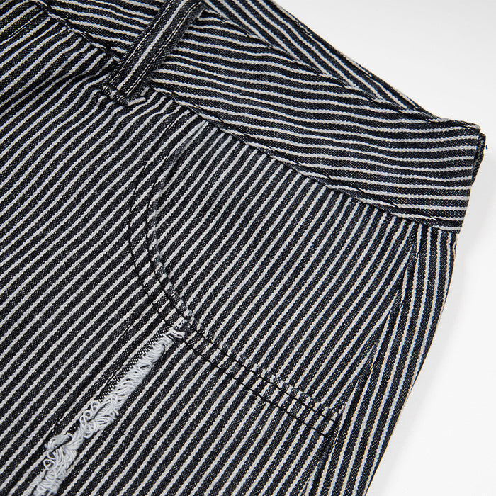 Close-up of a flap pocket and frayed vertical seam on black and white striped jeans