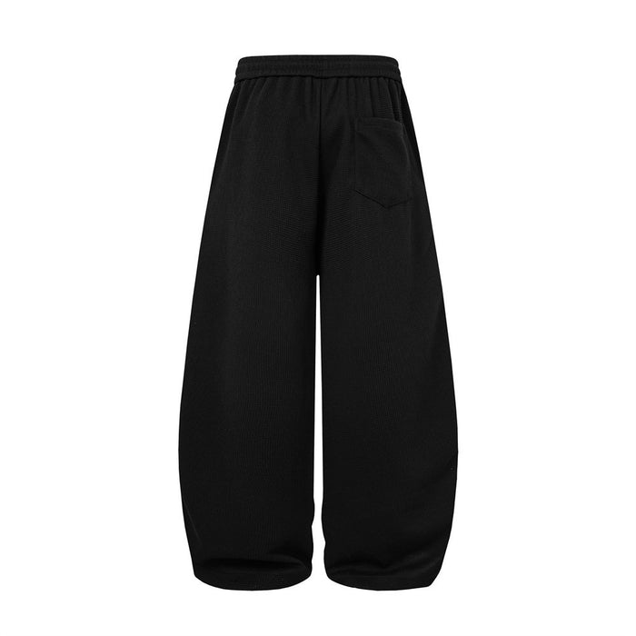 Back view of black waffle-knit wide-leg sweatpants with an elastic waistband and plain legs
