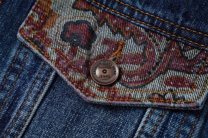 Close-up of a paisley jacquard chest pocket flap with a metal button on dark blue denim
