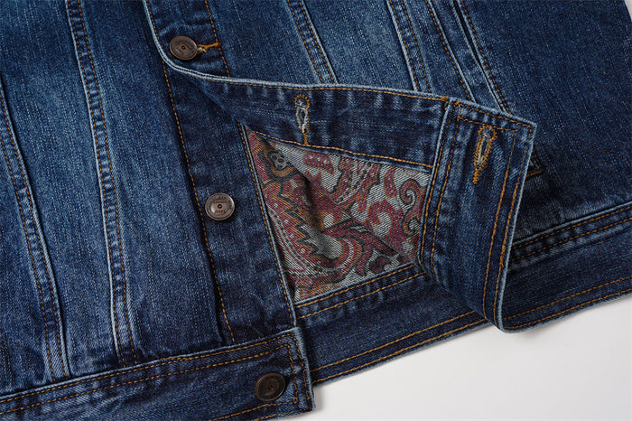 Inside lower jacket detail showing a paisley-lined pocket, denim panels, buttons, and hem stitching