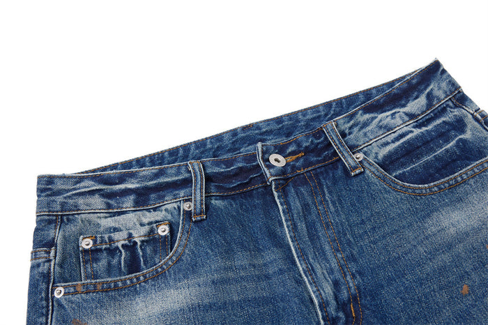 Close-up of the front waistband, belt loops, button, pockets, and faded blue denim