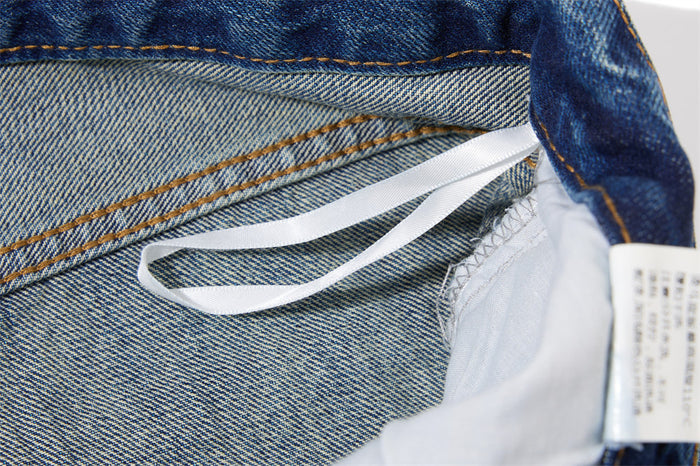 Close-up of the jeans interior showing a white fabric label and stitched denim waistband