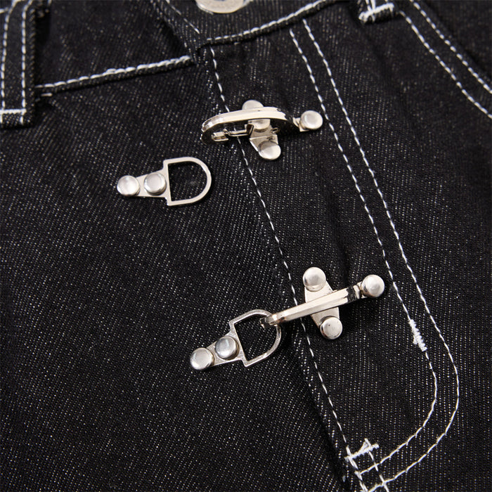 Close-up of silver clasp closures on black jeans with prominent white contrast stitching