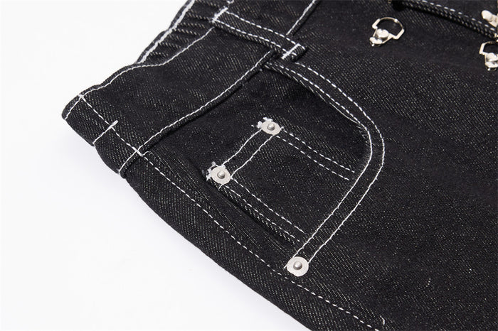 Close-up of a black cargo jeans pocket with white stitching and silver snap details