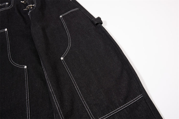 Close-up of a black jeans leg showing an outlined cargo pocket and side fabric strap