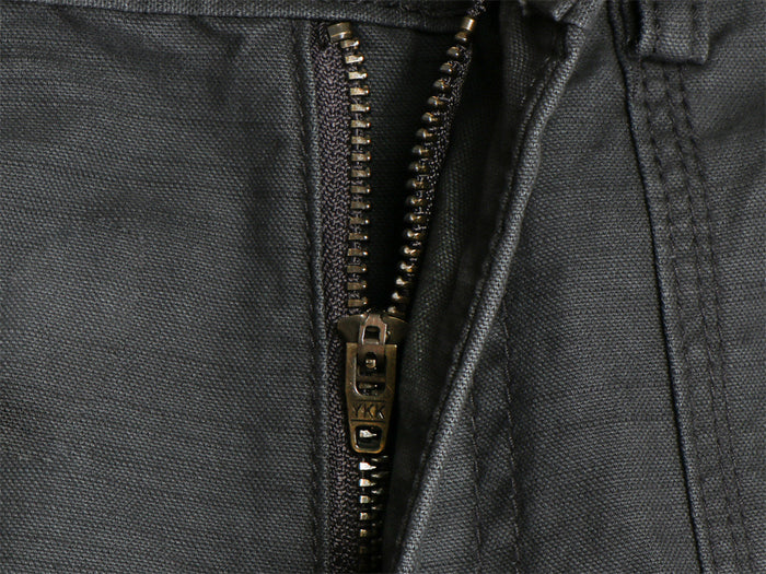 Close-up of the dark gray cargo pants metal zipper and textured woven fabric
