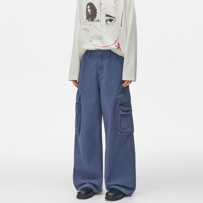 Front model view of washed blue cargo trousers with symmetrical thigh pockets and wide hems