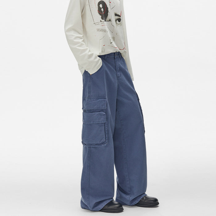 Angled front view of blue wide-leg cargo pants highlighting the side cargo pockets and slanted hand pocket