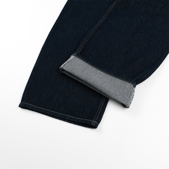 Close-up of wide-leg dark indigo jeans hem with a rolled cuff revealing the lighter gray underside