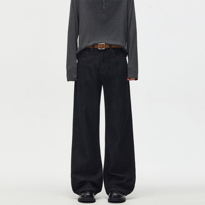 Front view of black wide-leg raw denim jeans worn with a dark long-sleeve shirt and black shoes