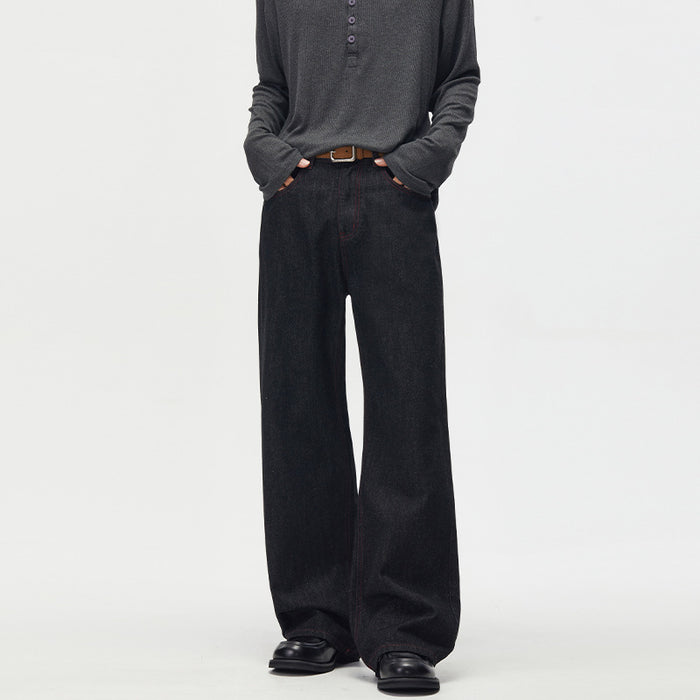 Front view of black wide-leg jeans with hands in the front pockets and contrasting red stitching