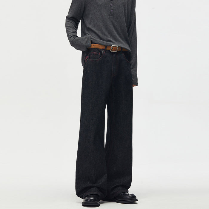 Angled front view of black wide-leg denim jeans showing curved front pockets and brown belt