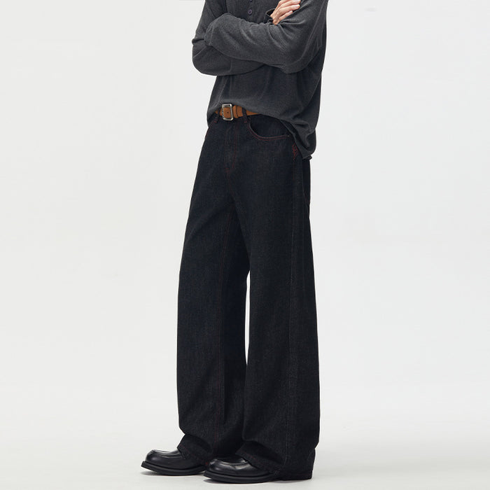 Side view of black wide-leg raw denim jeans showing the relaxed straight leg and front pocket