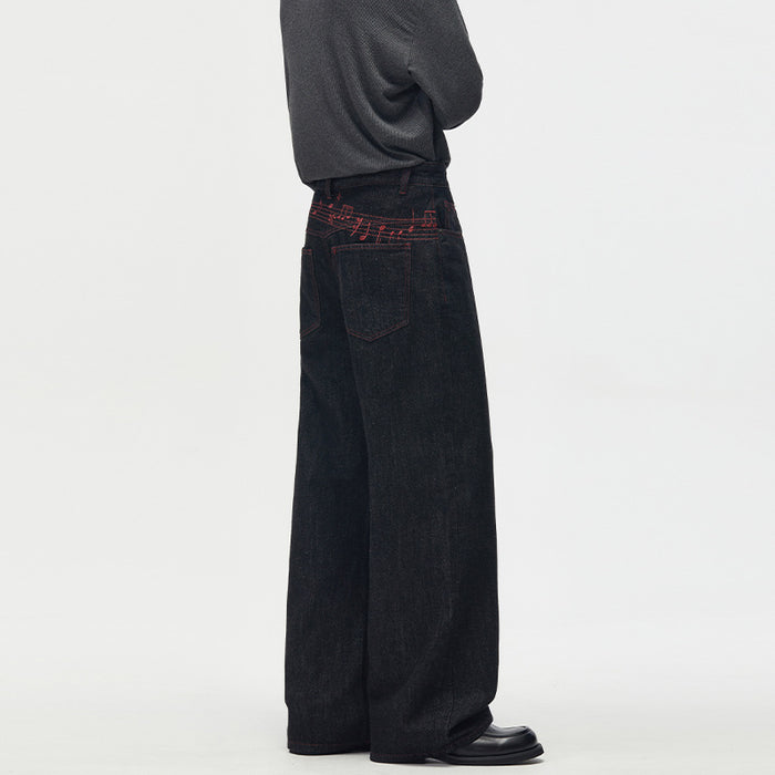 Angled back view of black wide-leg denim jeans with patch pockets and red stitched music notes