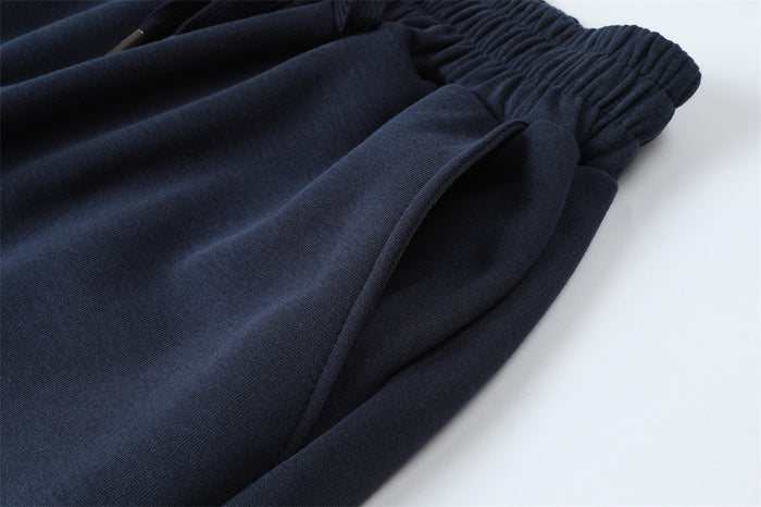Close-up of the navy sweatpants side seam and curved front hand pocket