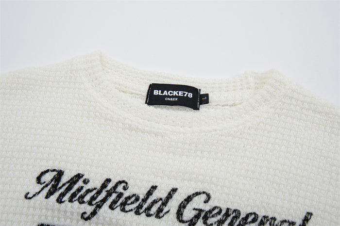Close-up of the white waffle-knit shirt collar, BlackEyePatch label, and embroidered Midfield General script