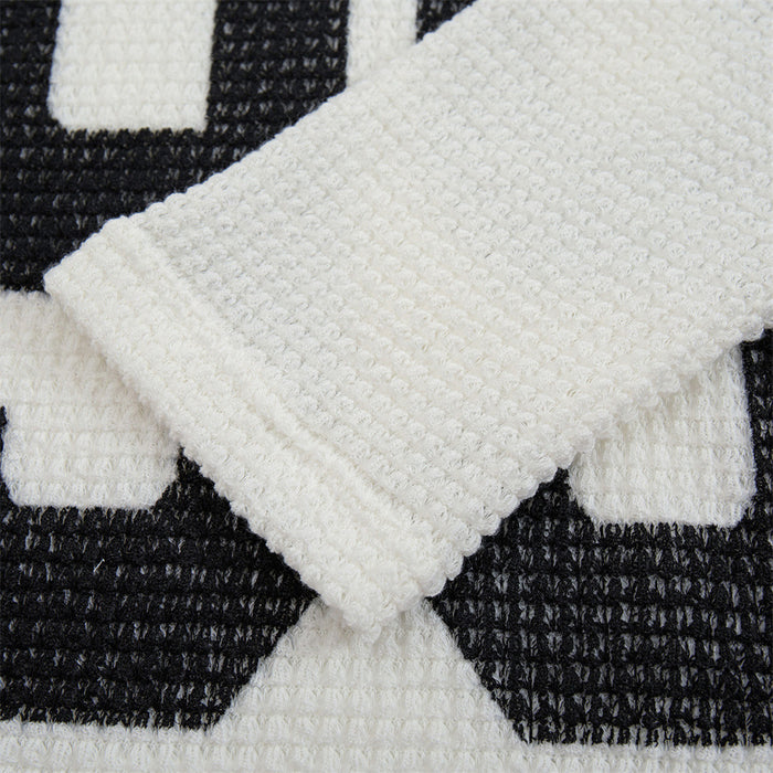 Close-up of a white waffle-knit sleeve overlapping the black 99 chest graphic
