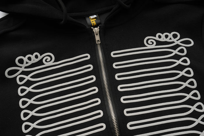 Close-up of white baroque braid graphics bordering the silver front zipper on the black hoodie