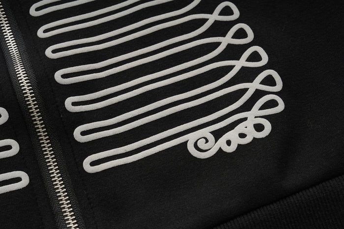 Close-up of the white looping braid pattern and black textured fabric on the hoodie front