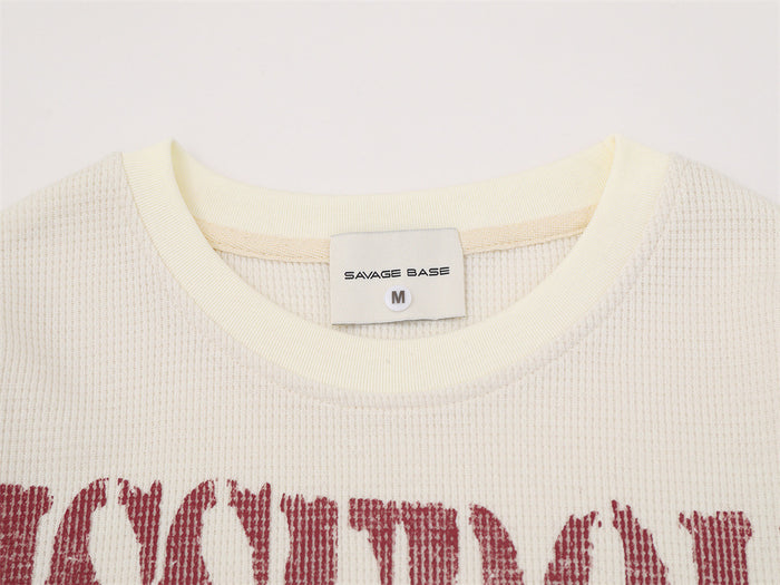 Close-up of cream shirt collar with ribbed trim, sewn label, and red distressed lettering