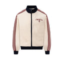 Front view of a cream waffle-knit track jacket with navy collar, zipper, hem and cuffs, red stripes and chest embroidery
