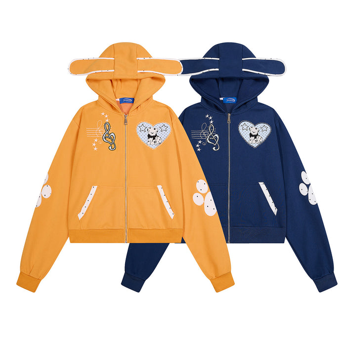 Front view of navy and orange cropped zip-up hoodies with ear-shaped hoods, musical note graphics, dog heart patches and paw prints