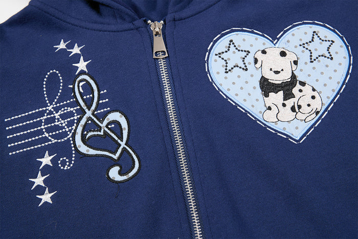 Close-up of navy hoodie chest graphics showing a musical note, stars, zipper and dog inside a heart patch