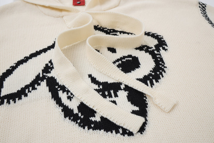 Close-up of cream hoodie drawstrings over the black knitted animal face graphic