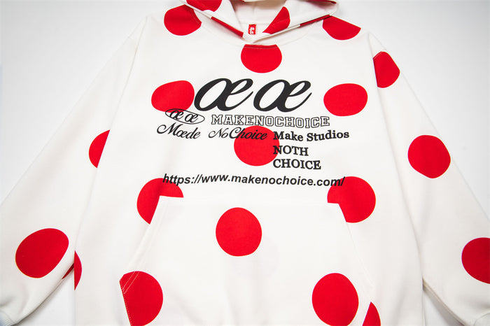 White polka dot hoodie laid flat, showing its red all-over print, hood, sleeves, and front lettering