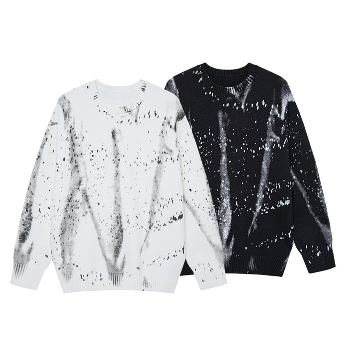 White and black knit crewneck sweaters with contrasting gray paint-splatter streaks shown together from the front