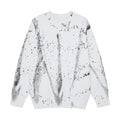 Oversized crewneck knit sweater with all-over black ink-wash and paint splatter print on white base, front view