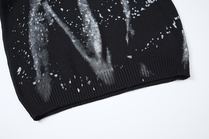 Close-up of the black sweater’s ribbed bottom hem with gray streaks and scattered white speckles