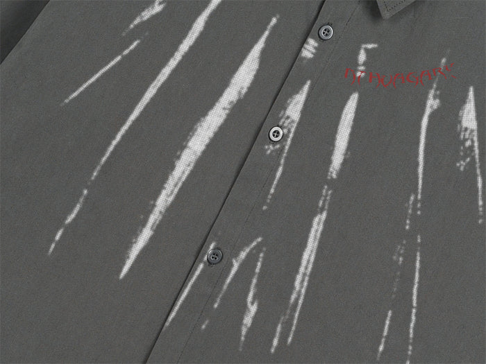 Close-up of white paint-stroke graphics, red lettering, and buttons on the black shirt front