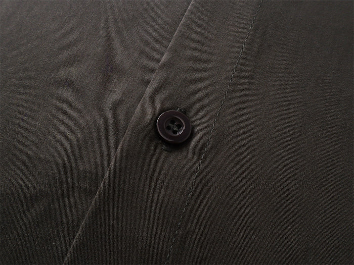 Close-up of a dark shirt button set against fine textured fabric and a stitched seam
