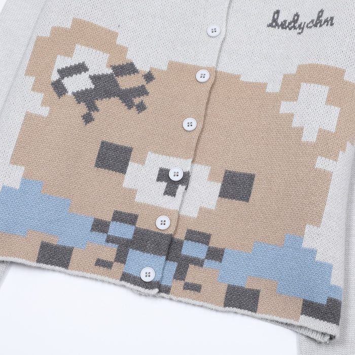 Close-up of the light gray cardigan's pixel bear knit graphic, white buttons, and textured jacquard stitching