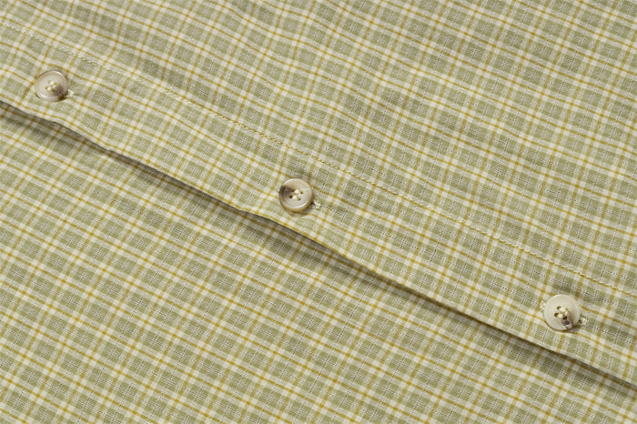 Close-up of cream buttons along the olive plaid shirt front placket