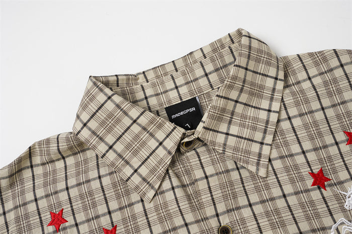Close-up of the beige plaid shirt collar, neck label, red embroidered stars, and partial white chest design
