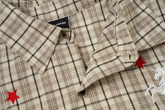 Beige plaid shirt front detail showing the pointed collar, dark buttons, red stars, and partial embroidery