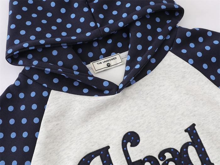 Close-up of the polka dot hood and shoulder seam with textured front lettering partially visible