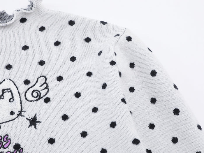 Close-up of the white polka dot knit shoulder and sleeve with part of the cat graphic