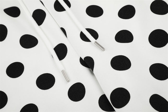 Close-up of white drawstrings with metal tips against the black polka dot pants fabric